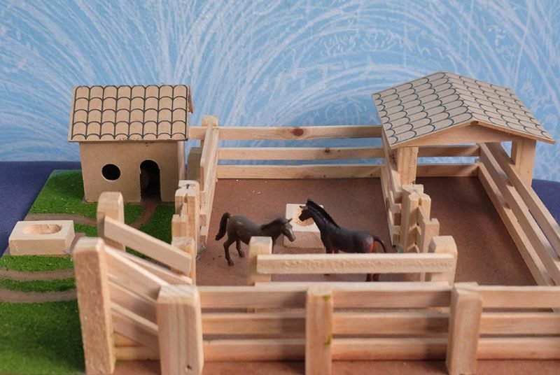 Brinquedos de madeira em miniatura com cerquinha e cavalos usados em sessão de psicanálise infantil em São Paulo.