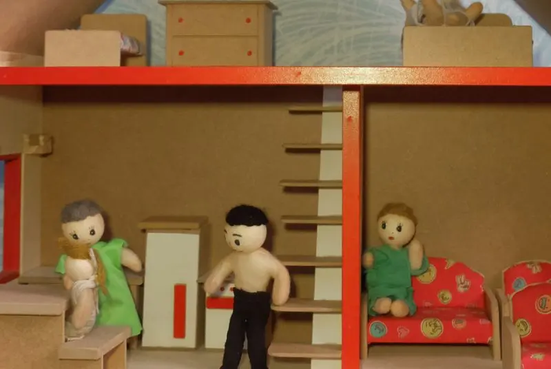 Casa de bonecas em miniatura com pequenos bonecos de pano e madeira usada em consultas de psicanálise infantil em São Paulo.